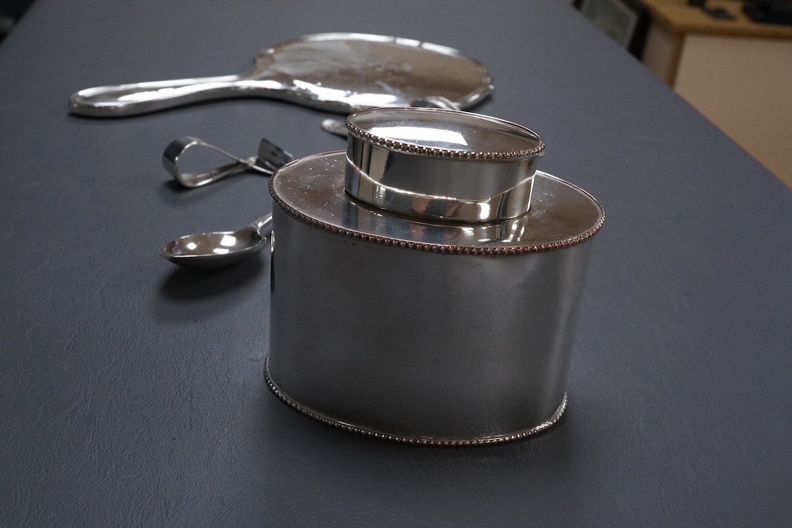 A George V silver mounted hand mirror, a silver spoons and pusher, a silver christening fork and spoon and a silver plated tea caddy.